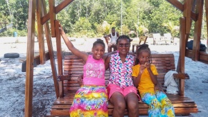 a woman and two girls sitting together on a swinging bench outside