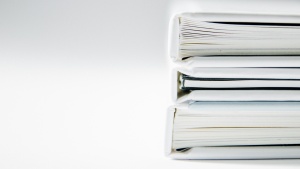 Photo of documents in stacked binders on white table.