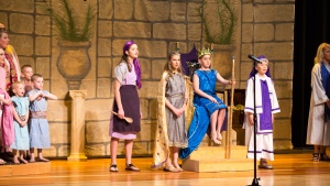 Right to left: the choir, Brooklyn Booth plays the narrator/palace cook, Cadence Phelps as Queen. Jedidiah, James Morris sits on his throne as Josiah, and Aaron Preston as Hilkiah. 