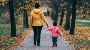 a woman and a child walking on a path surrounded on either side with autum foliage