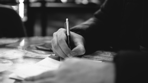 a hand with a pen writing on paper