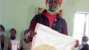 Lucia Mulenga holds up a nearly finished doormat.