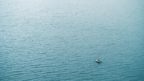 A tiny boat in a big sea of water.