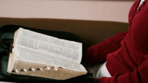 A woman reading a Bible on her lap.