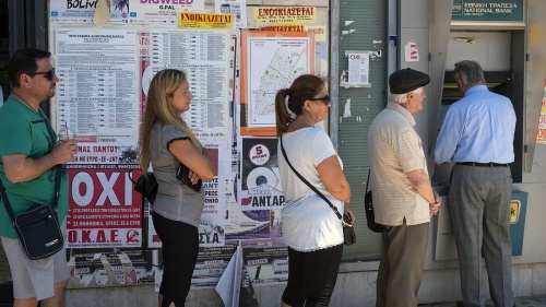 People waiting in line in to use a bank ATM.