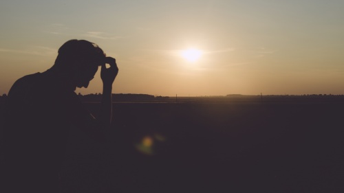 A man sitting with the sun in the background.