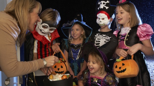 Little children dressed up in Halloween costumes trick or treating.