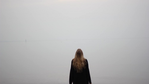 A woman standing by herself looking up.