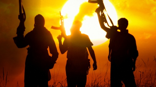 Three men holding machine guns in the air.