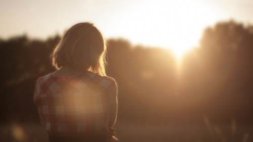 A girl sitting outside looking at sunset.