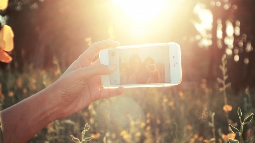 Two young women taking a "selfie" of themselves with the bright sun glaring. 