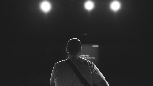 The back of a man looking at stage lights.