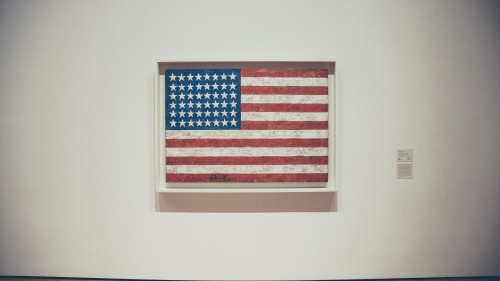 A framed old American flag hanging on a museum wall.