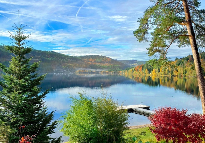 a bright blue lake and sky surrounded by green hills and trees