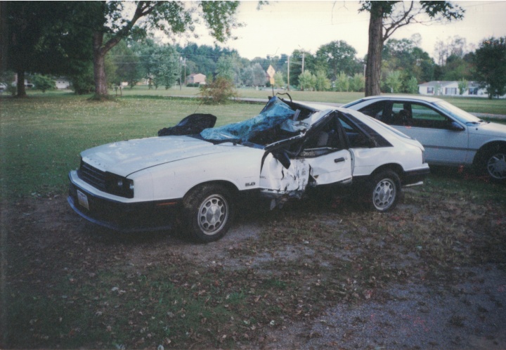 Totaled white car with roof collapsed in and glass shattered