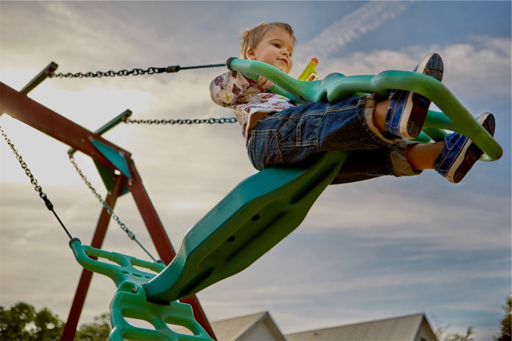 A little boy swinging on a swingset.