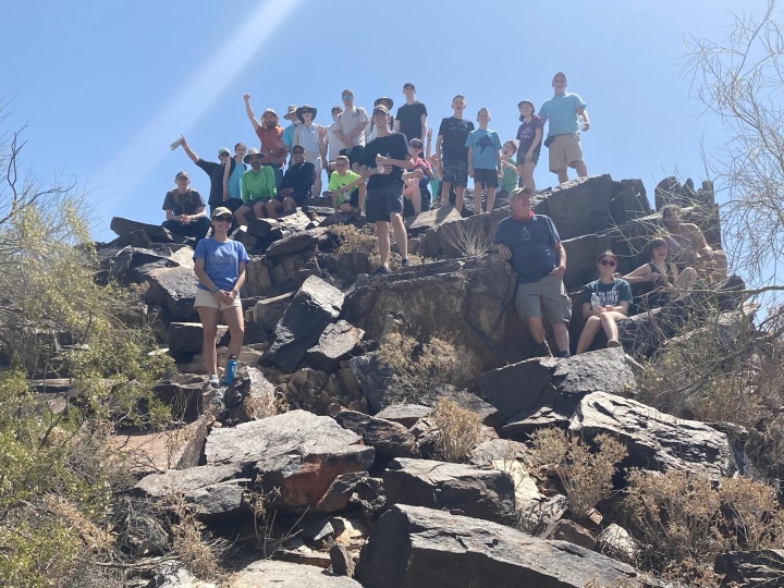 A group of hikers standing and seated on boulders