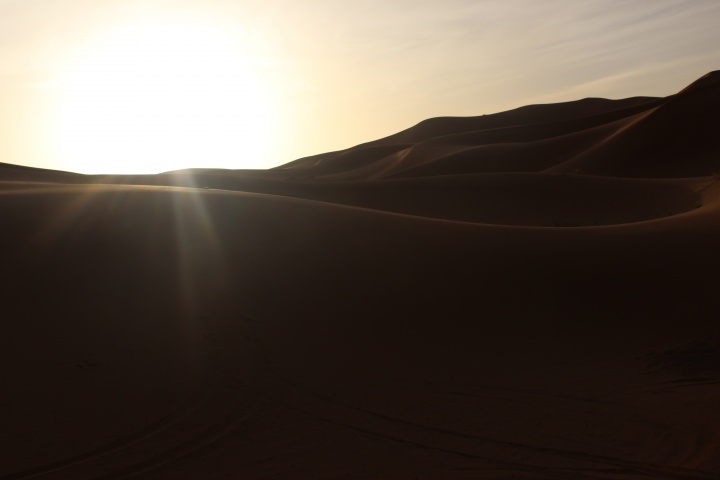 Desert mountains with the bright sun in the distance.