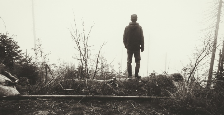 A young man walking in a foggy forest.