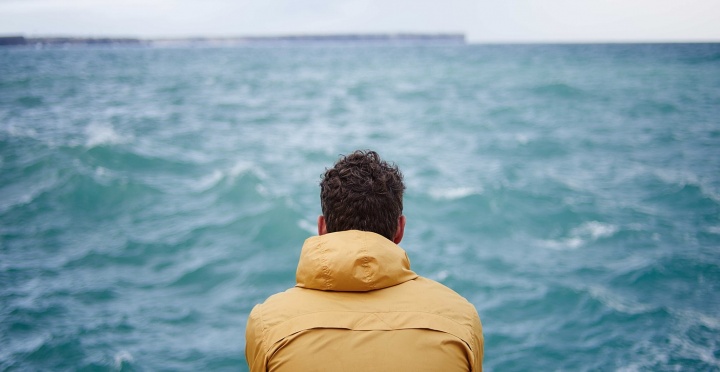 A man watching the waves on a lake.