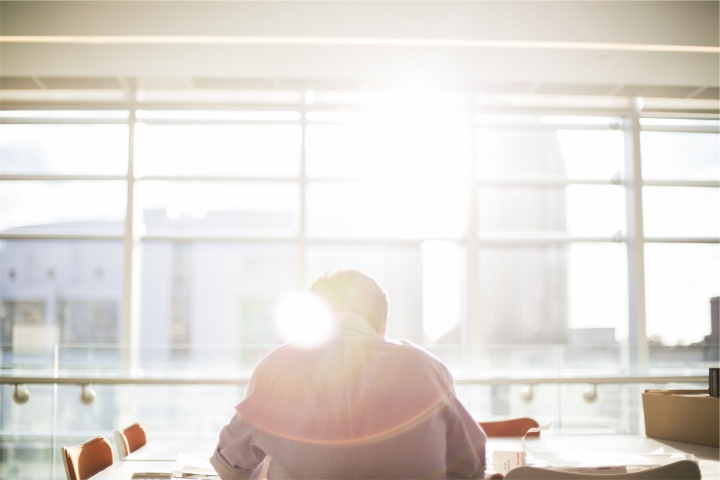 A person sitting at a table with sun rays coming in from a window.