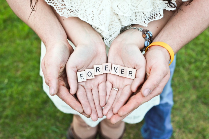 A young married coupling holding in the hands Scrabble letters that spell FOREVER