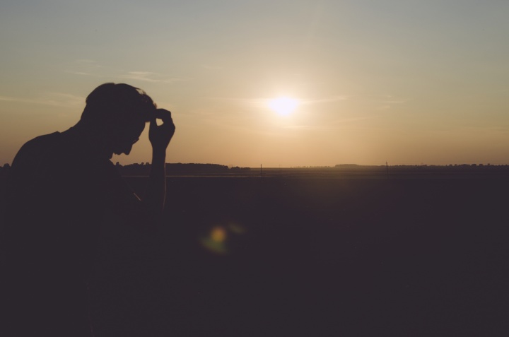 A man sitting with the sun in the background.