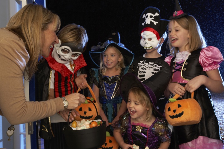 Little children dressed up in Halloween costumes trick or treating.