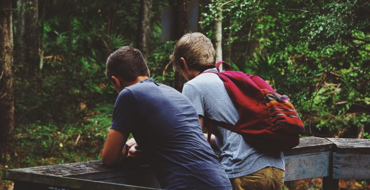 Two young boys together hiking in the woods.