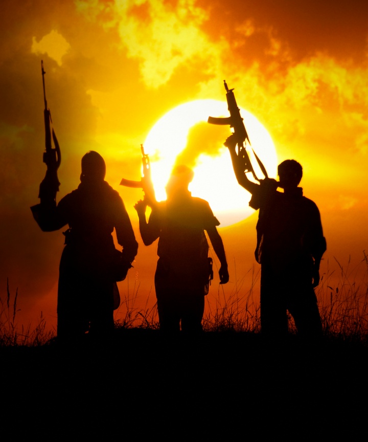 Three men holding machine guns in the air.