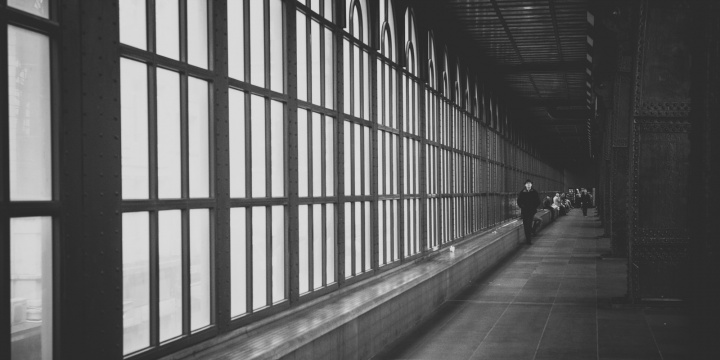 A long hall lined by windows with people walking in the distance.