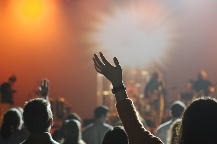 People with their arms up in the air worshiping while music is playing.