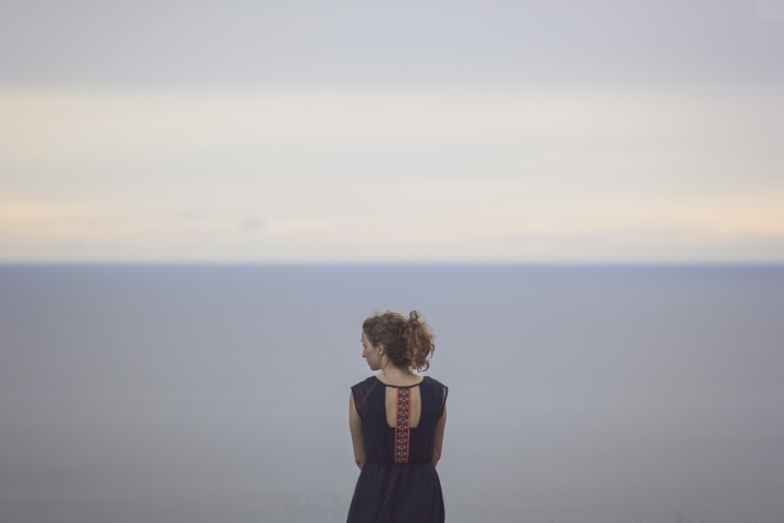 A young women looking at the ocean.