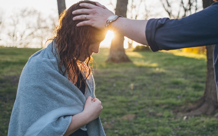 A woman with hands being laid on her in prayer after water baptism.