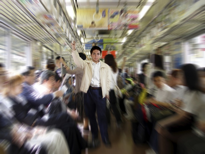 A man surrounded by people on a subway car.