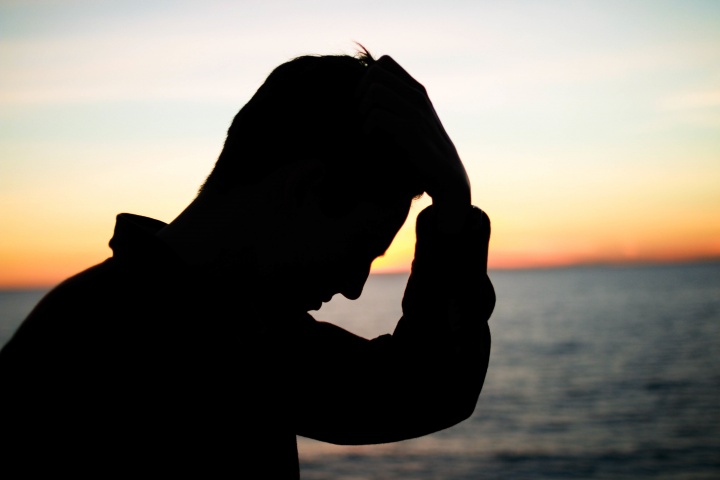 A silhouette of a man with his hand on his head.