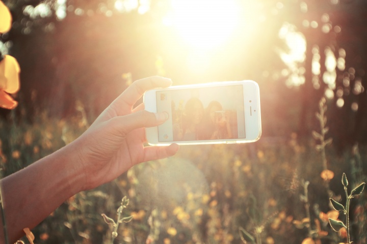 Two young women taking a "selfie" of themselves with the bright sun glaring. 