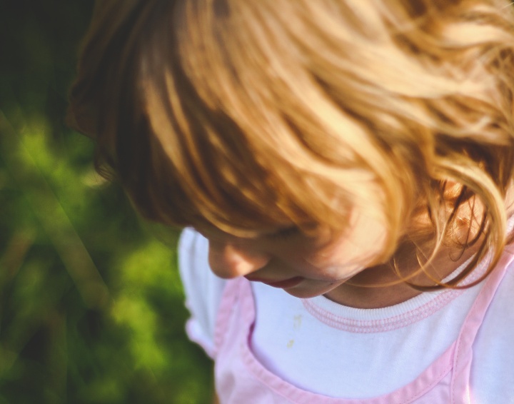 A little girl looking down at the ground.