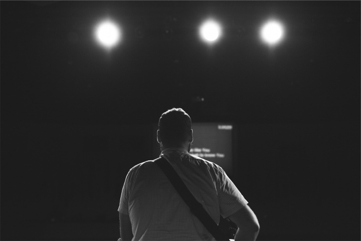 The back of a man looking at stage lights.